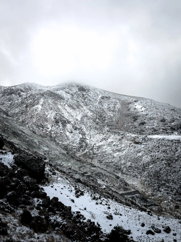 A snow-covered mountain slope under clouds