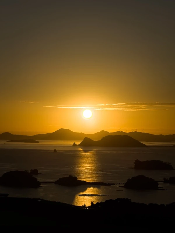 The sun setting over islands in the sea