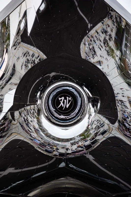 A mirrored sculpture reflecting the people below